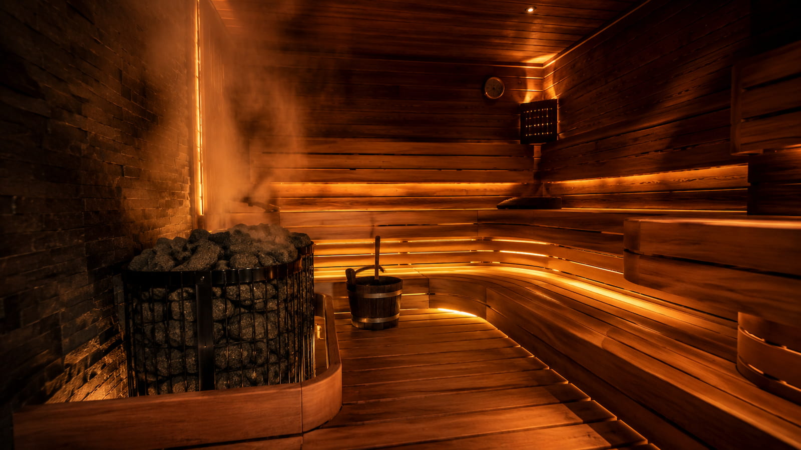 Interior of a traditional Finnish sauna with wooden benches, steam rising, and warm amber lighting — the kind of daily health practice Bryant Wimmer uses for brain and cardiovascular health